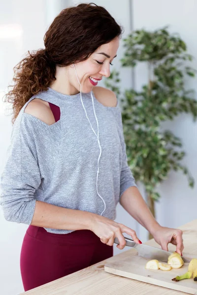 Genç ve güzel kadın kesme muz mutfak müzik dinlerken kadeh.