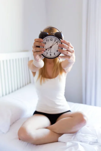Foto Mujer Joven Bonita Sosteniendo Reloj Despertador Mostrando Cámara Dormitorio — Foto de Stock