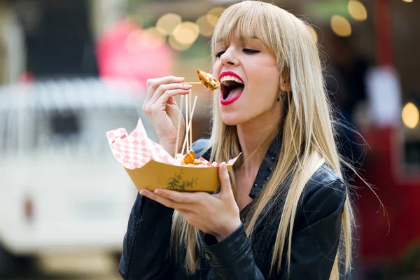 通りでポテトを食べるのはかなり若い女性のショット — ストック写真