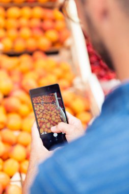 Bardak portakal sağlık bakkal dükkanında bir fotoğraf ile onun smartphone yapmasını satıcısı.