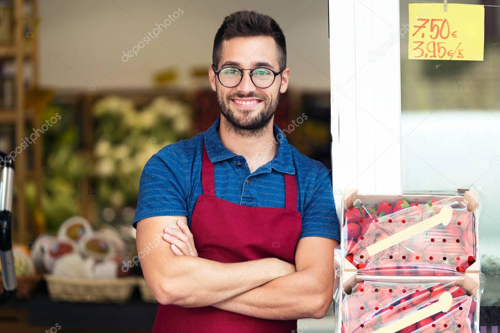 Portrait of handsome young salesman looking at camera in health grocery shop.