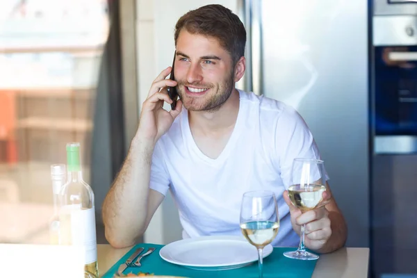 Tiro Jovem Bonito Falando Smartphone Enquanto Bebe Vinho Branco Cozinha — Fotografia de Stock