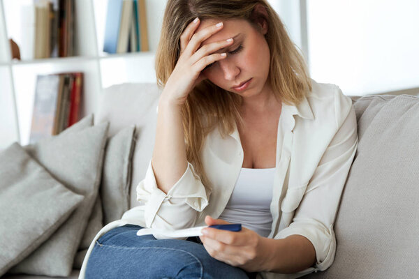 Снимок молодой женщины, испытывающей депрессию и грусть после просмотра результатов теста на беременность дома
.