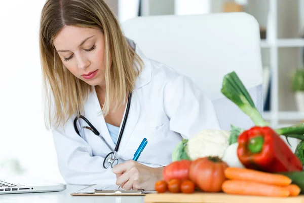 Tiro Belo Jovem Nutricionista Trabalhando Mesa Escrevendo Registros Médicos Sobre — Fotografia de Stock