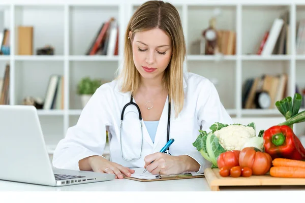 Tiro Belo Jovem Nutricionista Trabalhando Mesa Escrevendo Registros Médicos Sobre — Fotografia de Stock