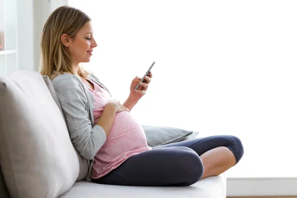 Tiro Hermosa Joven Embarazada Mensajes Texto Con Teléfono Inteligente Sofá —  Fotos de Stock