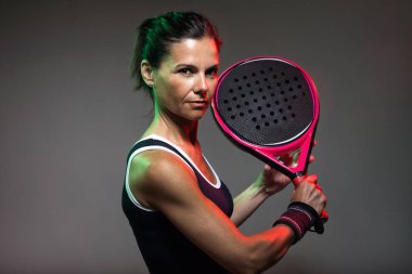 Kameraya padel kapalı oynarken seyir yetişkin fitness kadın portresi. Siyah izole.