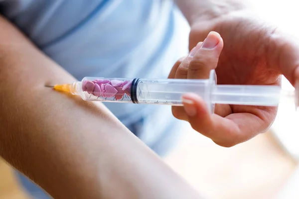 Young woman injecting syringe with sugar hearts in her arm. Concept of diabetes. — Stock Photo, Image