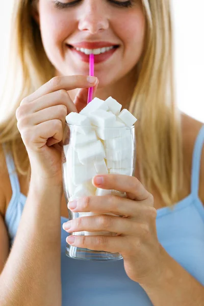 Beautiful young woman simulating to drink sugar in a glass cup over white background. — Stock Photo, Image