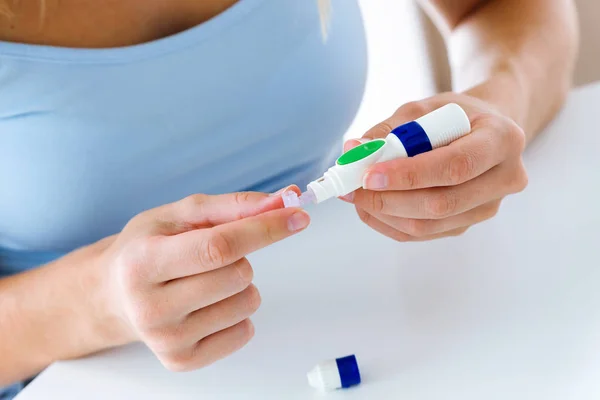 Mujer joven cambiando la aguja del lápiz para hacerse la prueba de glucosa en el fondo blanco . —  Fotos de Stock