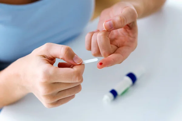 Young woman getting glucose test with glucometer at home. Incorrect process concept. — Stock Photo, Image