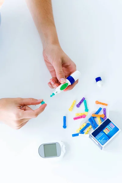 Jeune femme changeant d'aiguille au crayon pour se faire tester pour le glucose sur fond blanc . — Photo