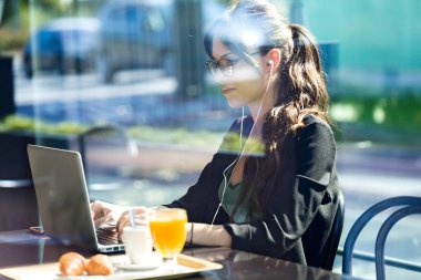 Bir kafede kahvaltı yaparken onu laptop ile çalışan güzel genç kadın.