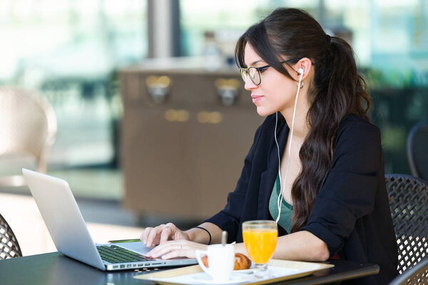 Красивая молодая женщина работает со своим ноутбуком за завтраком в кафе
.