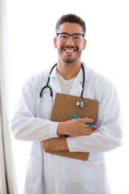Beyaz arka plan üzerinde izole Pano tutan boyun üzerinden stetoskop ile çekici genç erkek doktor portresi. 