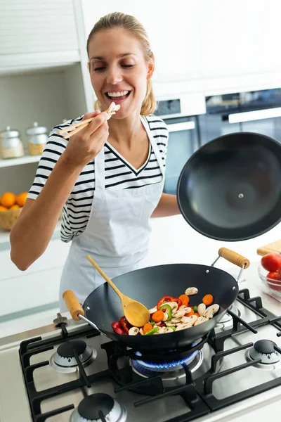 Tiro Mujer Joven Saludable Cocina Degustación Alimentos Con Cuchara Madera —  Fotos de Stock