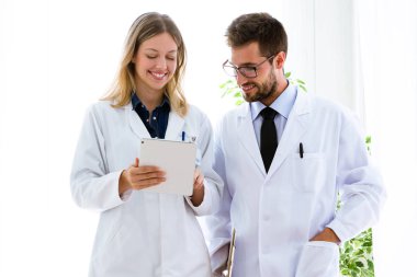 Gülümseyen genç doktorların tıbbi Office dijital tablet tıbbi raporlar arıyorsunuz.