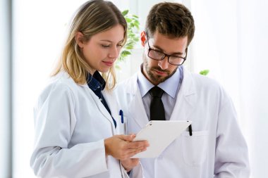 Tıbbi raporlar dijital tablet tıbbi ofis arayan genç emin doktorlar konsantre.