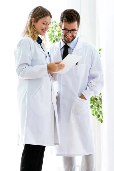 Uśmiechający się młodych lekarzy właśnie raportów medycznych w cyfrowy tablet w gabinecie lekarskim. — Zdjęcie stockowe