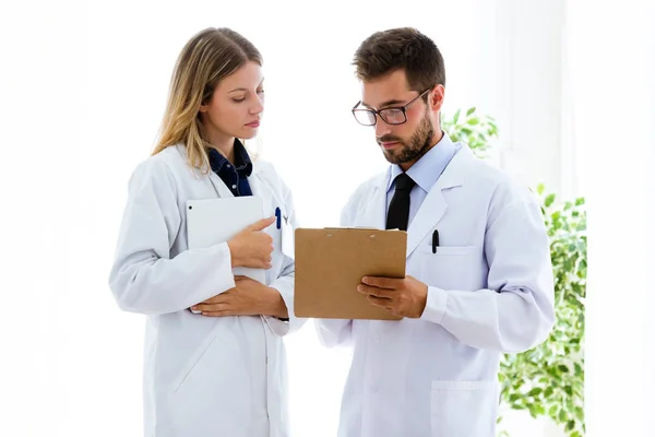 Уверенные врачи-женщины и мужчины записывают информацию в папку в медицинской консультации . — стоковое фото
