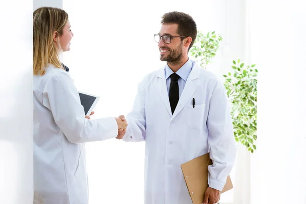 Wesoły oung uśmiechający się lekarze, drżenie rąk w gabinecie lekarskim. — Zdjęcie stockowe