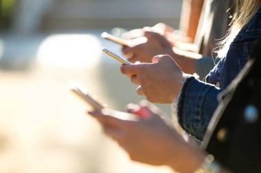 Genç grup arkadaşıyla çatırdamak ile onların akıllı telefonlar sokakta Close-up.