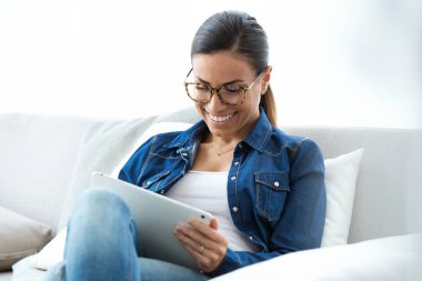 Mutlu genç kadın kanepe evde dijital tablet ile sohbet gözlük ile çekim.
