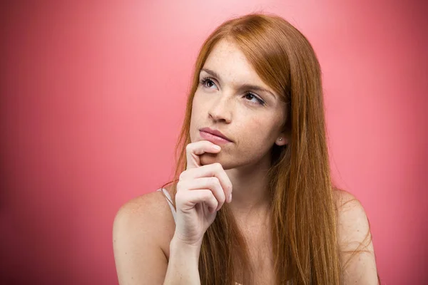 ピンクの背景を考えて 仕事のアイデアに興味深いの若い女性のショット — ストック写真