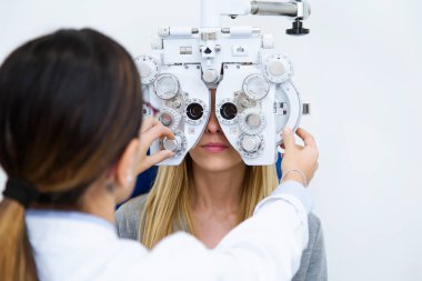 Genç kadının iskemlede güzel gözlükçü göz hastalıkları kliniği göz testi yaparken ayakta ile atış.
