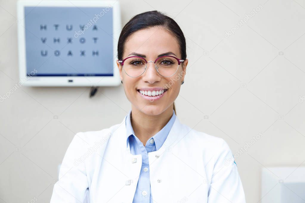 Portrait of pretty young woman ophthalmologist smiling while looking at camera in the consultation.