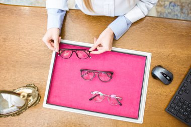 Close-up of ophthalmologist hands showing eyeglasses to customer in optic shop. clipart