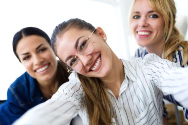 Üç güzel genç iş kadın dikiş atölyede cep telefonu ile bir selfie alarak atış.
