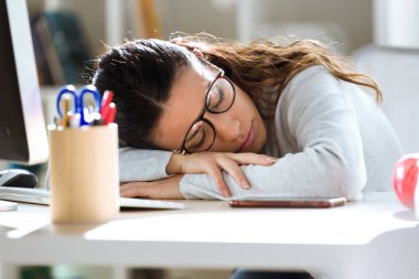 Ofiste çalışırken uykuya düşmüş genç iş kadını bitkin.