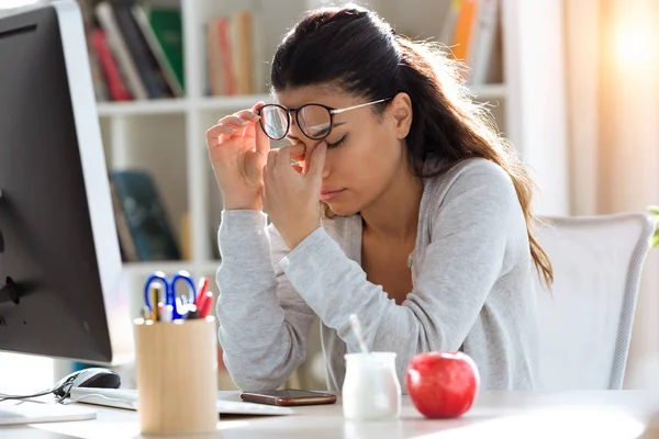 Trött ung affärskvinna med huvudvärk medan du arbetar med dator på kontoret. — Stockfoto
