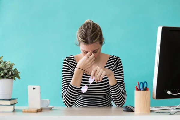 Mujer de negocios joven y cansada que tiene dolor de cabeza mientras trabaja con la computadora en la oficina . — Foto de Stock