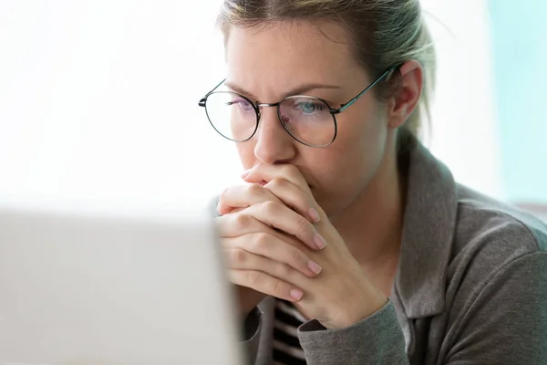 Concentre-se jovem mulher de negócios olhando seu computador enquanto pensa no escritório . — Fotografia de Stock