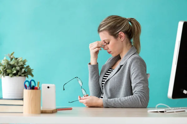 Trött ung affärskvinna med huvudvärk medan du arbetar med dator på kontoret. — Stockfoto