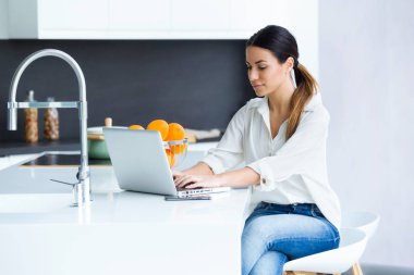 Genç ve güzel kadın mutfakta evde onu laptop kullanarak çekim.