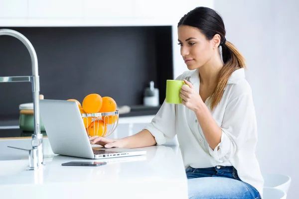 Tiro Mulher Muito Jovem Usando Seu Laptop Enquanto Bebe Xícara — Fotografia de Stock