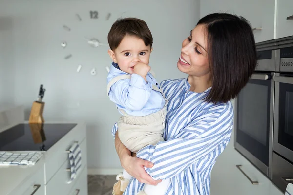 Fotografía Hermosa Madre Mirando Bebé Mientras Mira Cámara Cocina Casa —  Fotos de Stock