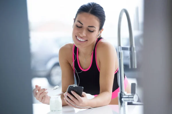 Atış Sportif Genç Kadın Mutfakta Evde Yoğurt Yerken Cep Telefonu — Stok fotoğraf