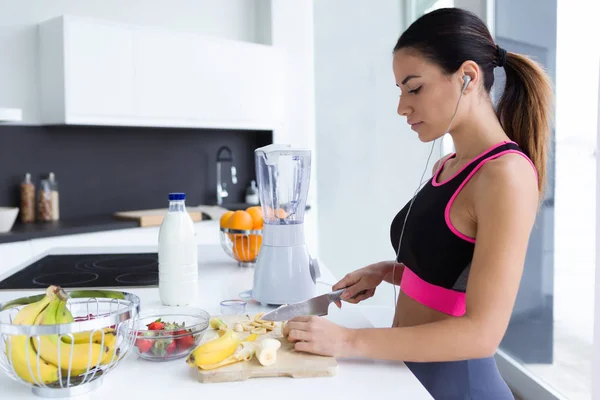 Tiro Mujer Joven Deportiva Cortando Plátano Mientras Escucha Música Cocina — Foto de Stock