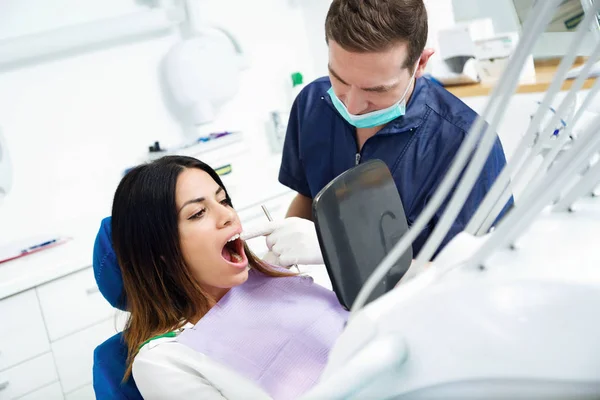 魅力的な若い歯科医と歯科医院で ミラーでのホワイトニング治療の結果を見て満足している患者のショット — ストック写真