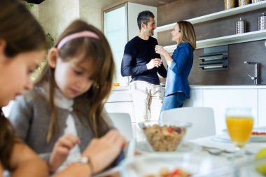 Atış güzel şirin kız evde mutfakta ebeveynleri ile Kahvaltı yaparken dijital tablet kullanma.