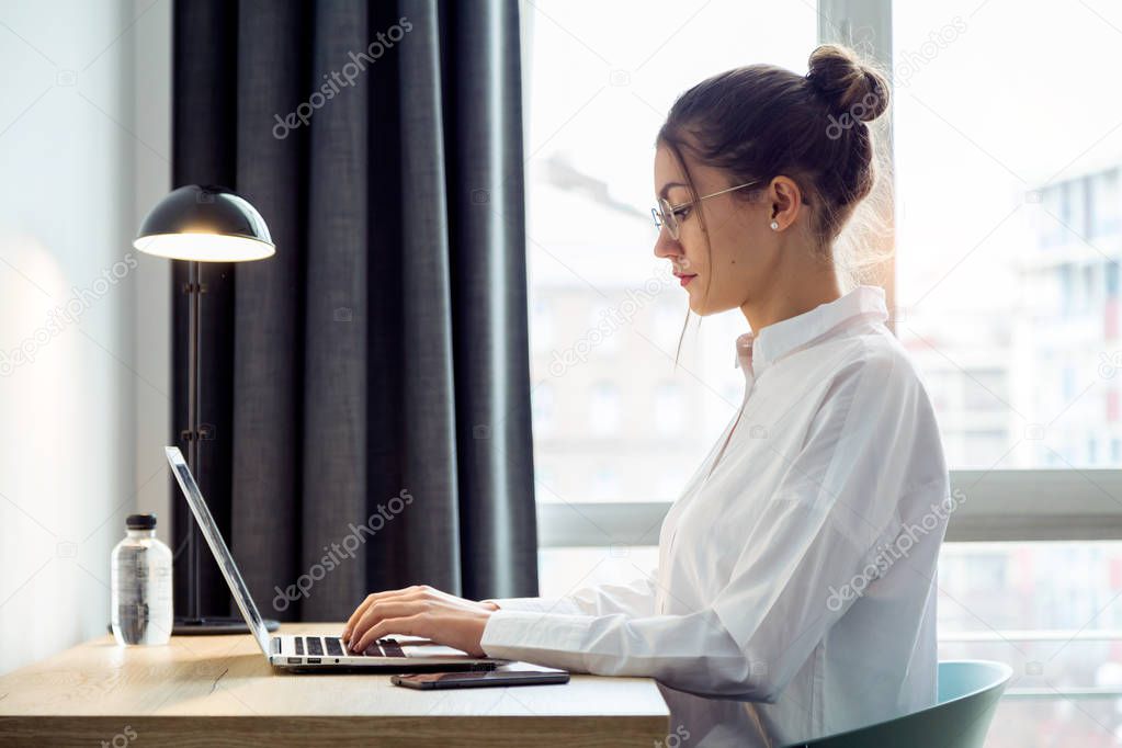 Shot of concentrated beautiful businesswoman working with her laptop on the desk at the hotel room.