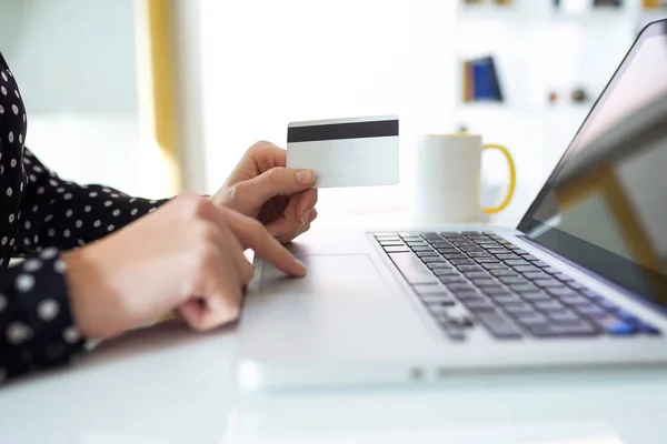 妇女手持白色信用卡在家中用电脑购物的特写镜头 — 图库照片