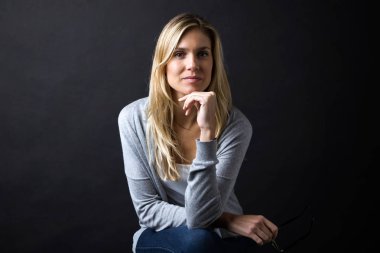 Kendine güvenen genç kadın kameraya siyah arka plan üzerinde seyir.