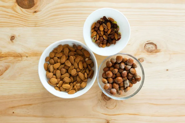 Different types of nutes in bowls on wooden table at home.
