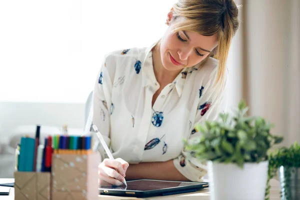 Mujer de diseño joven hermosa inteligente dibujando algo en su tableta digital en la oficina . —  Fotos de Stock
