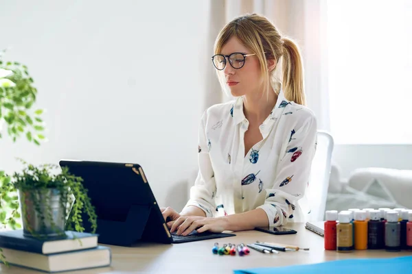 Mujer de diseño joven y concentrada trabajando con su tableta digital en la oficina . — Foto de Stock